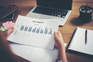 Person analyzing sales report data for customer insights, highlighting typical metrics used in customer analysis dashboards.