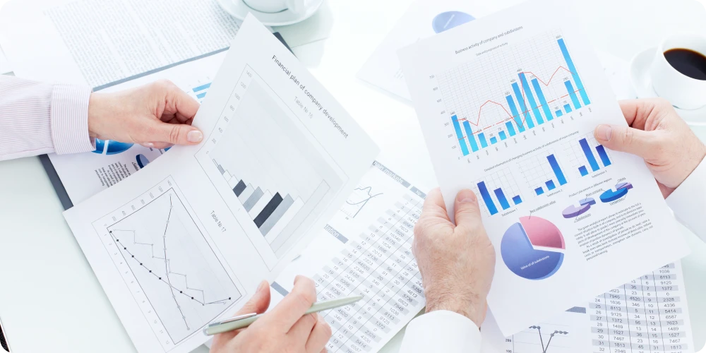 Two people analyzing a dashboard with revenue and volume charts, discussing data to boost revenue growth.