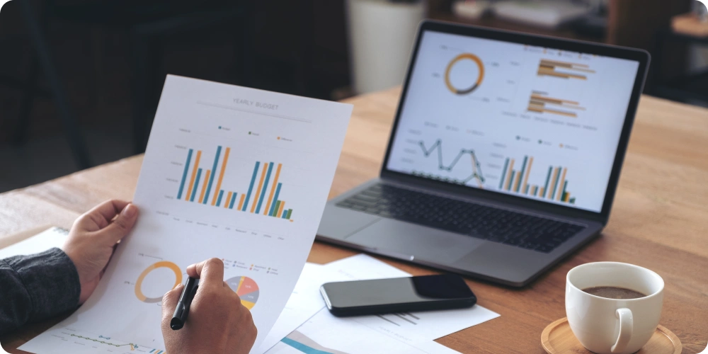 Analyzing customer data on a laptop with charts and graphs, tracking customer attrition and retention for CargoWise users.